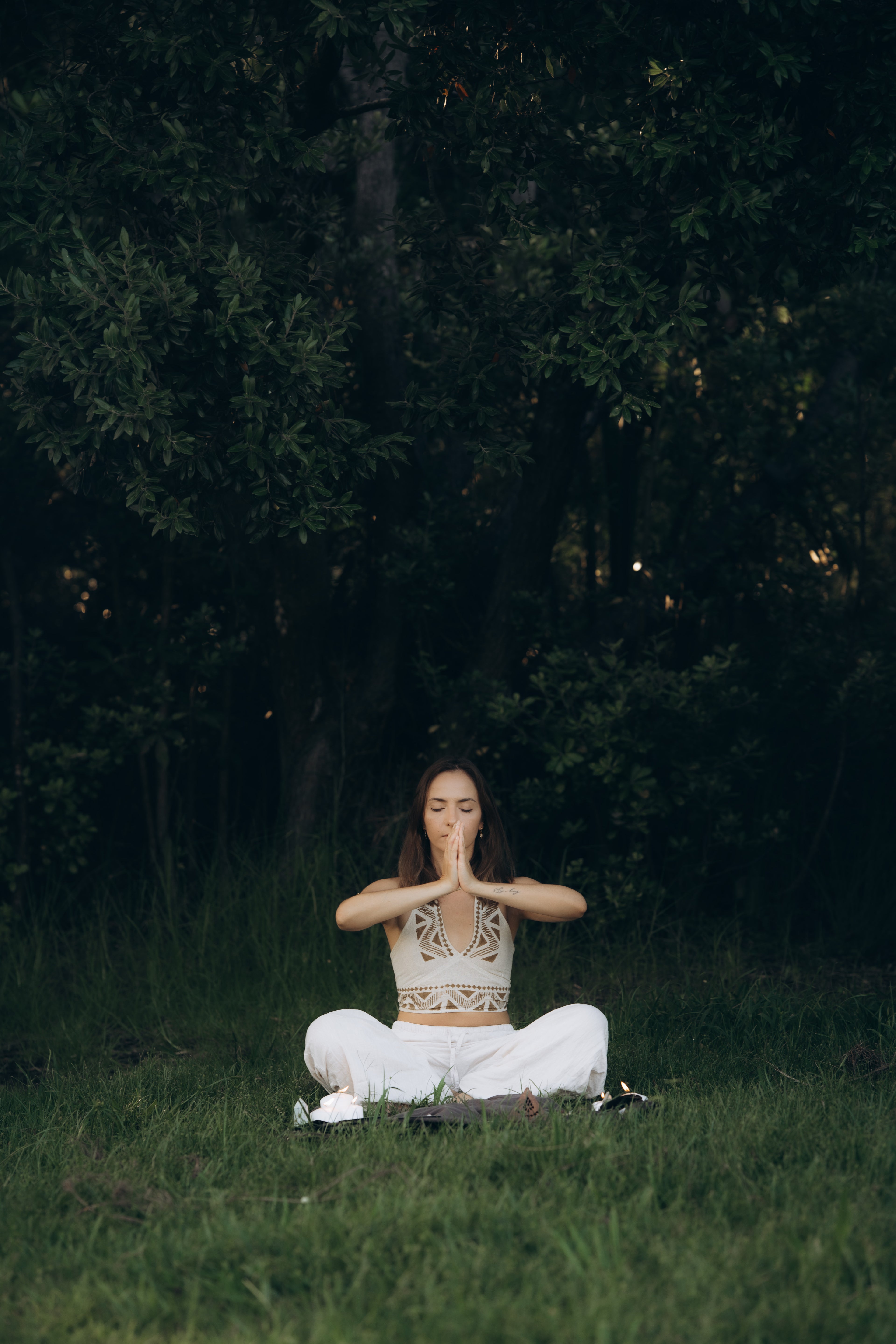 Assai Asha meditating in a natural setting with trees in the background